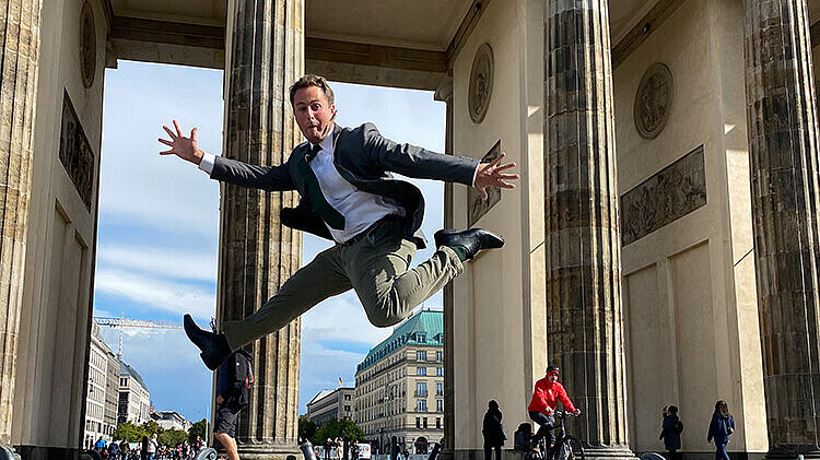 junger Mann springt vor Brandenburger Tor Berlin